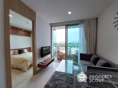 Bright and airy combined living and bedroom space with modern furnishings, leading to a sunny balcony with a serene view.