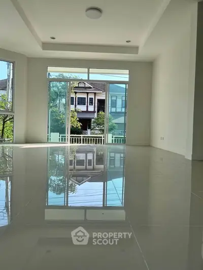 Spacious modern living room with large windows and glossy floors offering a serene view of the neighborhood.