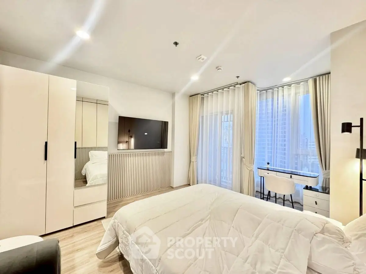 Modern bedroom with elegant decor and city view, featuring a cozy bed, sleek wardrobe, and stylish desk area.