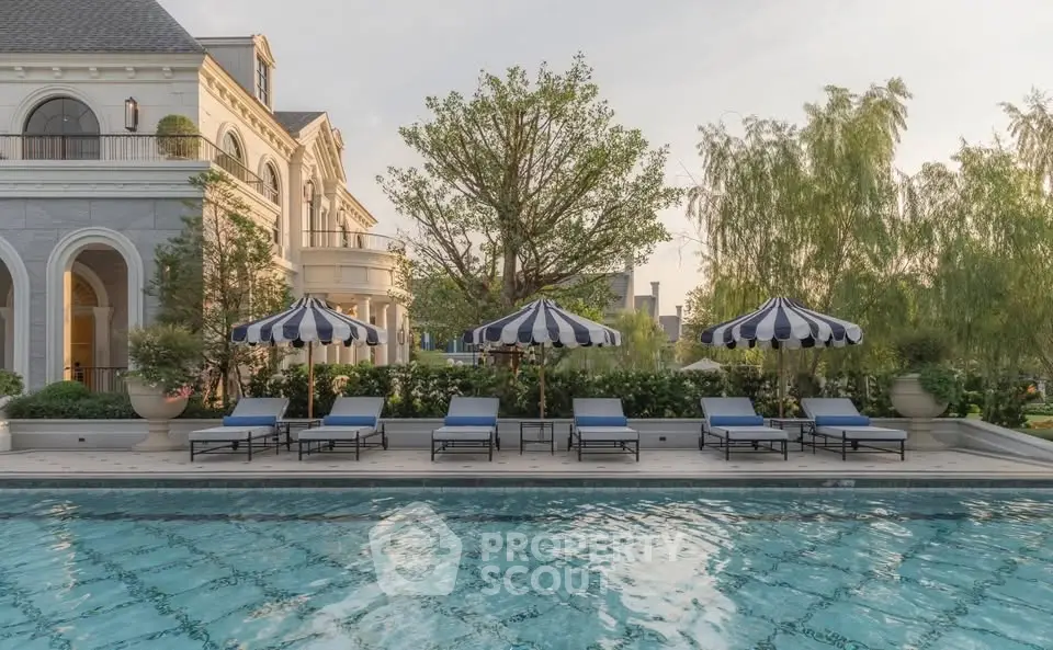 Luxurious mansion with elegant poolside and stylish loungers, perfect for upscale living.
