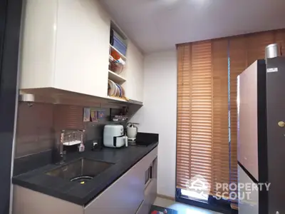 Modern kitchen with sleek cabinetry and appliances, featuring natural light through wooden blinds.