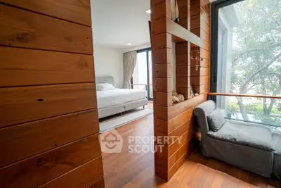 Modern bedroom with wooden accents and large windows offering natural light and serene views.