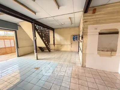Spacious open-plan interior with tiled flooring and staircase, ideal for renovation.