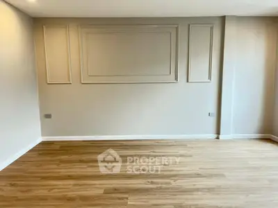 Spacious empty room with elegant wall paneling and wooden flooring, perfect for customization.