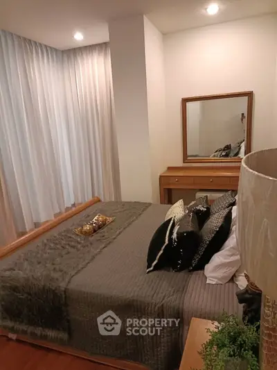 Cozy bedroom with elegant decor and soft lighting, featuring a stylish bed and mirror.