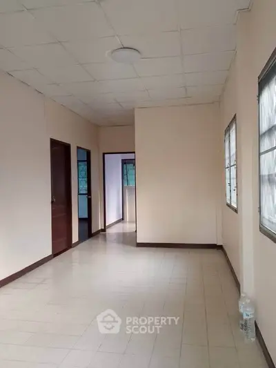 Spacious empty room with tiled flooring and natural light from windows, ideal for customization.