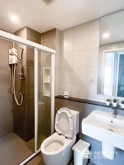 Modern bathroom with sleek glass shower enclosure, pristine white fixtures, and neutral tile design, offering a clean and contemporary living experience.