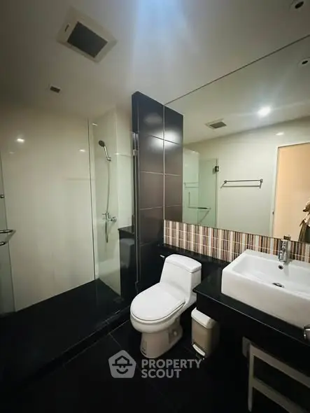 Modern bathroom with sleek design, featuring a glass shower and stylish sink.