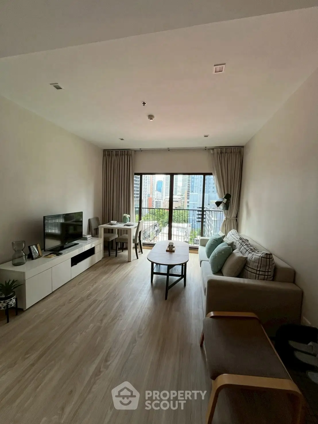 Spacious living room with city view, modern furniture, and natural light.