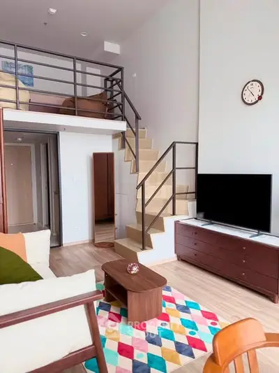 Modern loft-style living room with mezzanine, vibrant rug, and sleek furniture.