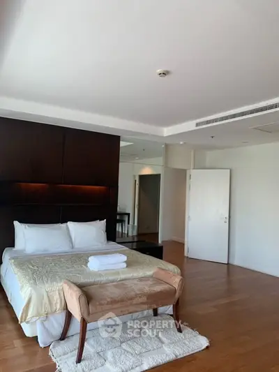 Spacious bedroom with modern decor and wooden flooring in luxury apartment.