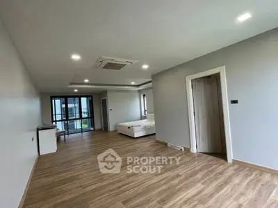 Spacious modern bedroom with wooden flooring and large windows in a luxury apartment.