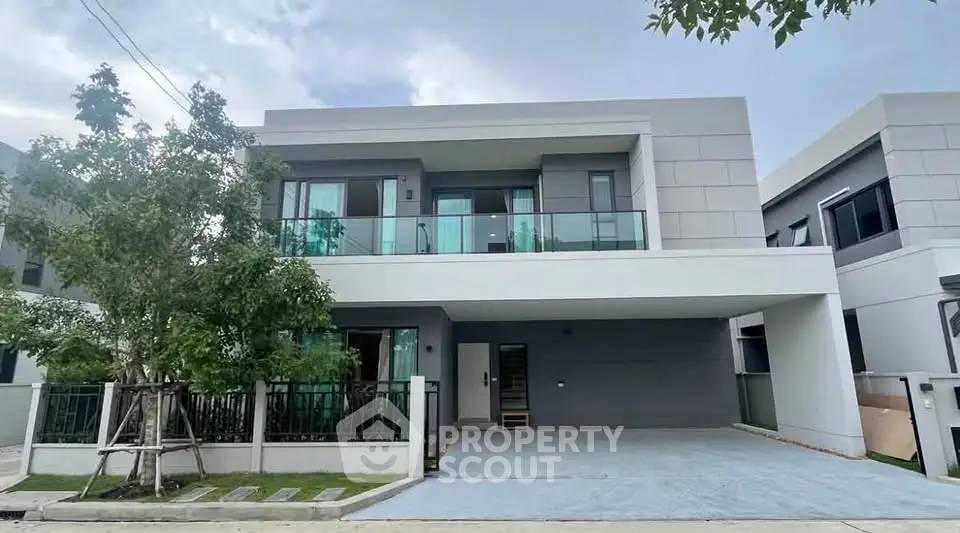 Modern two-story house with large balcony and driveway in a suburban neighborhood.