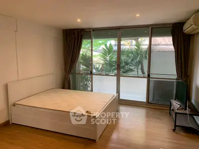 Spacious bedroom with large windows and garden view, featuring a minimalist design and ample natural light.