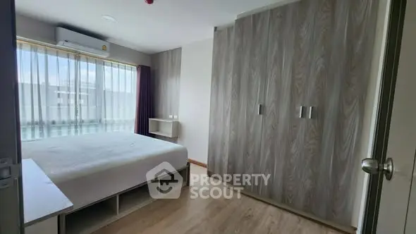 Spacious bedroom with large window and built-in wardrobe in modern apartment.
