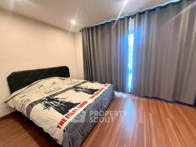 Spacious bedroom with wooden flooring and large window, featuring modern decor and ample natural light.