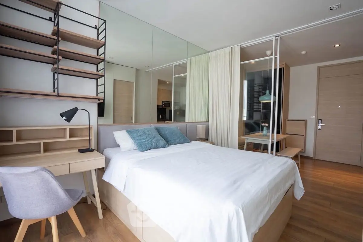 Modern bedroom with stylish decor and workspace, featuring a comfortable bed and wooden flooring.