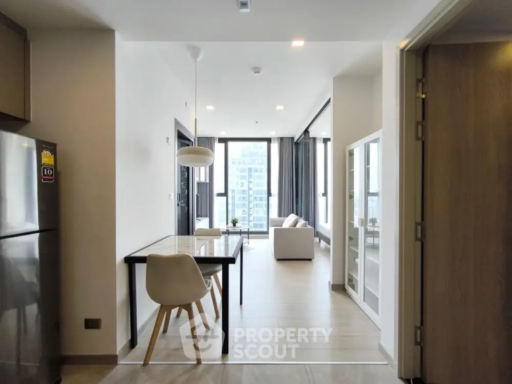 Modern open-plan living room with dining area and large windows in a stylish apartment.