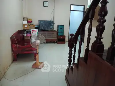 Cozy living room with wooden staircase and simple furnishings, ideal for a comfortable home setting.