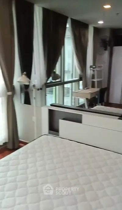 Spacious bedroom with large windows and modern decor in a luxury apartment.