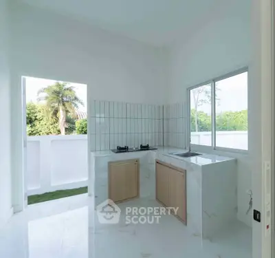 Modern kitchen with open layout and scenic view, featuring sleek countertops and large windows.