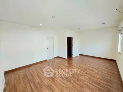 Spacious empty room with wooden flooring and white walls, perfect for customization.