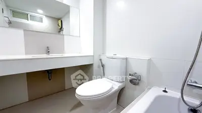 Modern bathroom with sleek white fixtures and bathtub in a contemporary home.