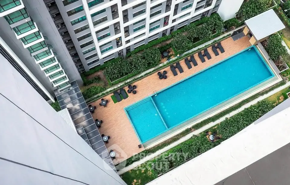 Stunning aerial view of modern apartment complex with luxurious swimming pool and lush greenery.