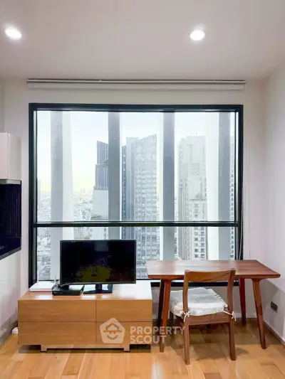 Modern living room with city view, featuring sleek furniture and large window for natural light.