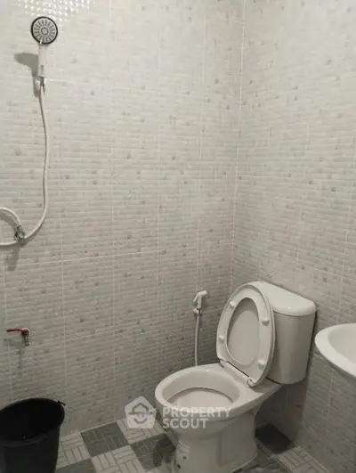 Modern bathroom with tiled walls and essential fixtures in a real estate property.