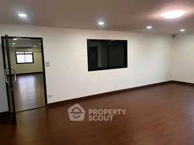 Spacious empty room with wooden flooring and large windows, ideal for customization.