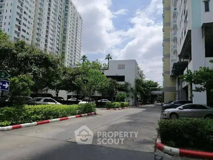 Modern residential complex with lush greenery and ample parking space.