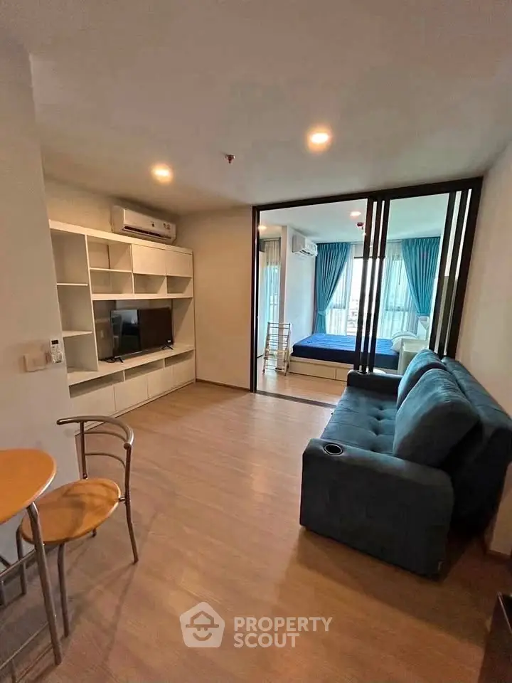Modern living room with blue sofa and sliding glass doors leading to a bedroom