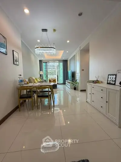 Spacious living room with elegant chandelier and modern decor in a high-rise apartment.