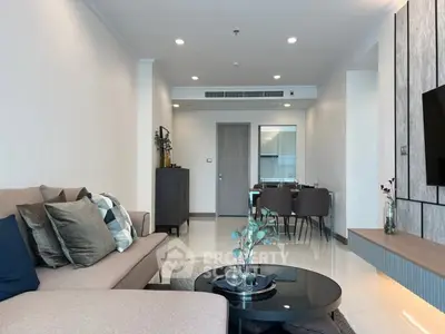 Modern living room with stylish decor and open dining area, featuring a cozy sofa and elegant table setting.