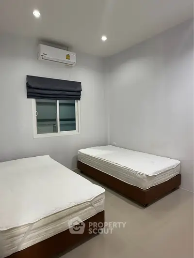 Minimalist bedroom with two single beds and air conditioning