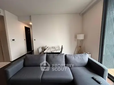 Modern living room with sleek gray sofa and dining area in open layout.
