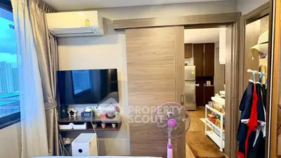 Modern apartment interior with sliding door, TV, and kitchen view, featuring stylish decor and efficient use of space.