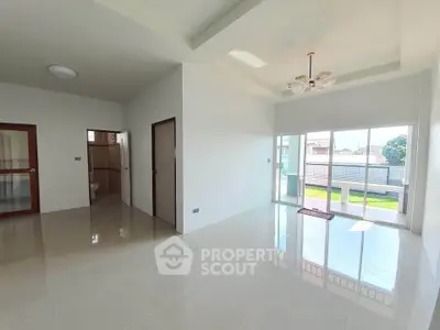 Spacious living room with large windows and glossy tile flooring, offering abundant natural light.