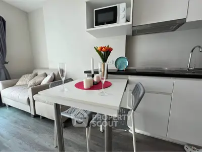 Modern kitchen with dining area and cozy living space, featuring sleek white cabinetry and stylish decor.