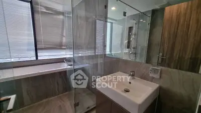 Modern bathroom with glass shower and bathtub, featuring sleek design and natural light.