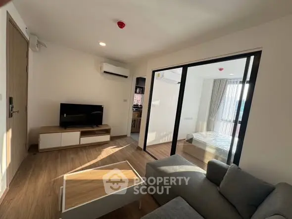 Modern living room with natural light and cozy furniture, adjacent to a stylish bedroom.