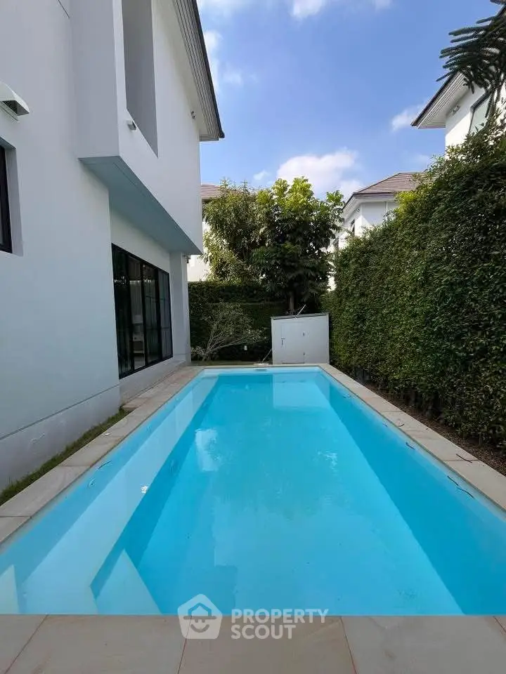 Luxurious private pool beside modern white house with lush greenery