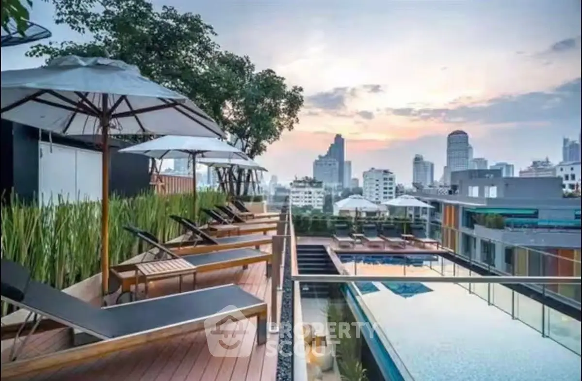 Luxurious rooftop pool with city skyline view and sun loungers at sunset.