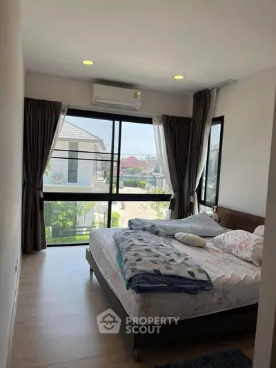 Bright bedroom with large windows and modern decor in a stylish home.