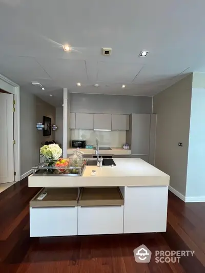 Modern kitchen with sleek island and wooden flooring in luxury apartment