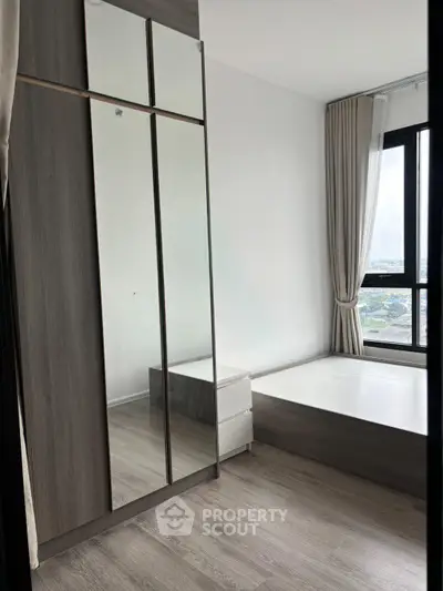Modern bedroom with large window and sleek wardrobe in high-rise apartment