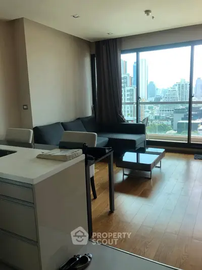 Modern living room with city view, featuring sleek furniture and large windows for natural light.