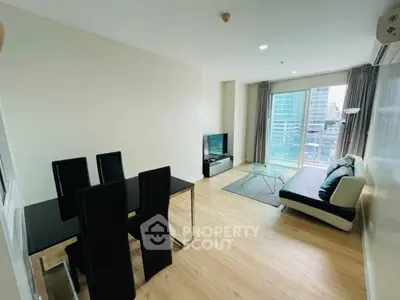 Modern living room with sleek furniture and city view balcony in a high-rise apartment.