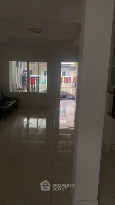 Spacious living area with glossy tiled floors and large window view.